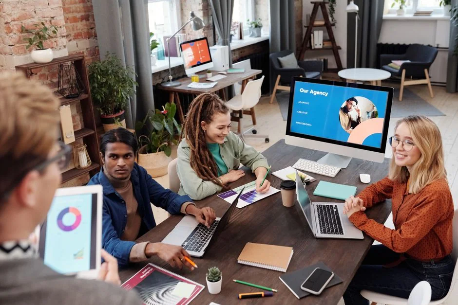 Un groupe varié travaille sur des stratégies marketing, avec des graphiques et des ordinateurs portables, dans un environnement de bureau.